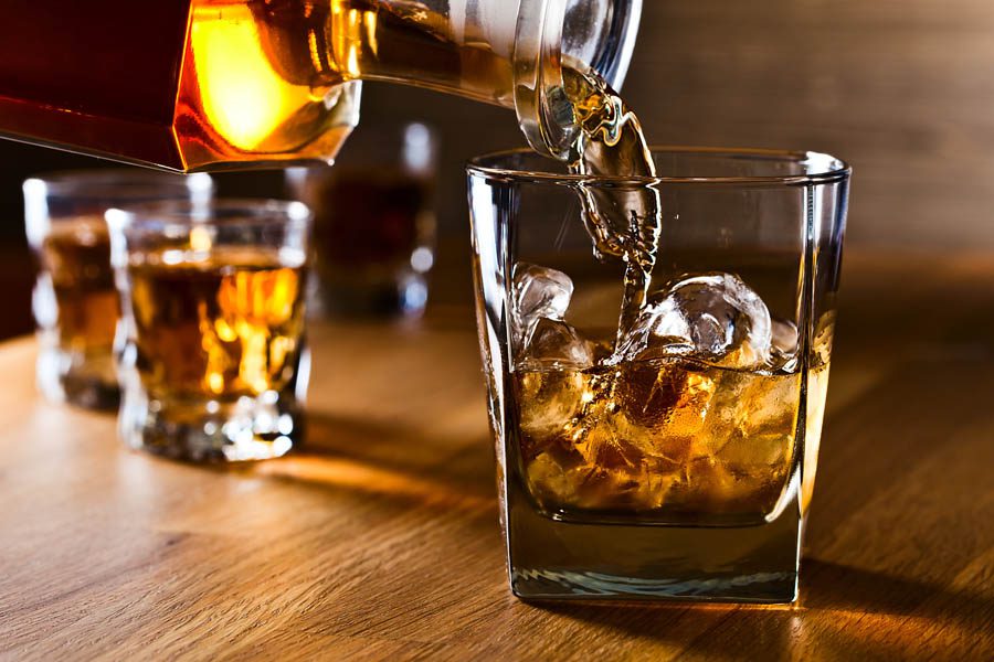 Distillery-Insurance-Pouring-Whiskey-Into-a-Bar-Glass-with-Fancy-Ice-Cubes